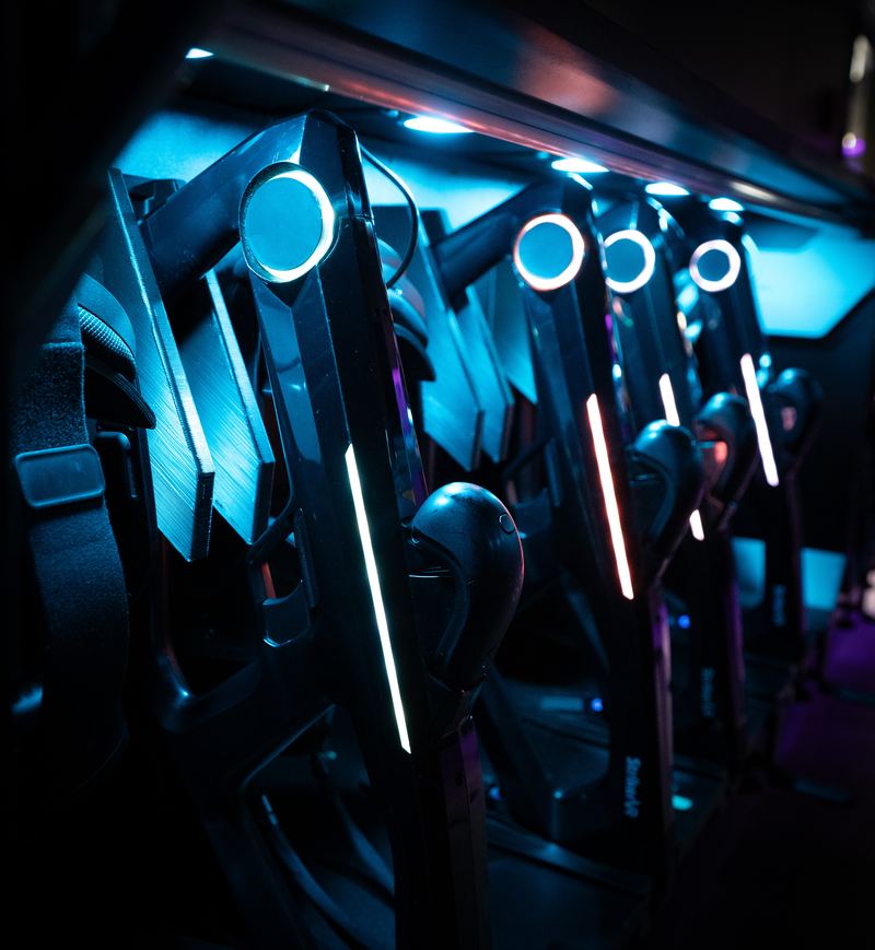 VR blasters with glowing rings racked on the arena wall.