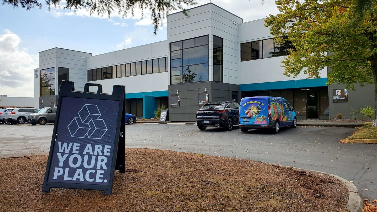 A sidewalk sign with the Dimension XR logo reading We are your place, outside the Tukwila building.